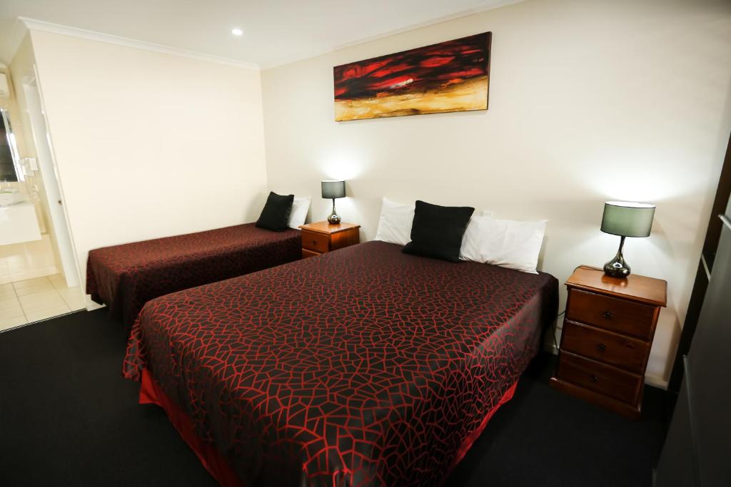 1 dormitorio con 2 camas y 2 mesitas de noche con lámparas en Amber Lodge Motel, en Gladstone