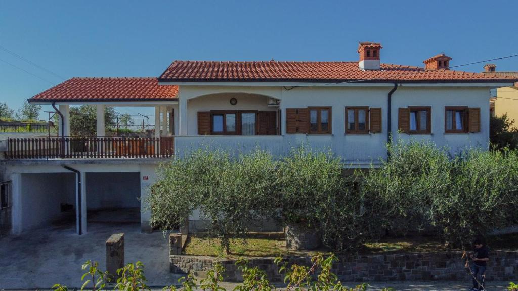 ein weißes Haus mit rotem Dach in der Unterkunft Apartma Tri oljke in Dobrovo