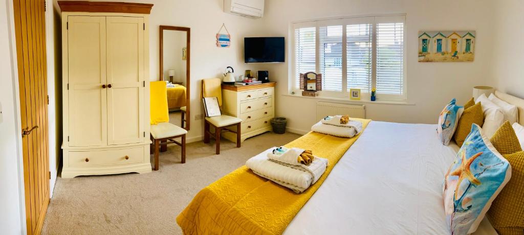 a bedroom with two beds and a dresser and a desk at Avon Beach Bed & Breakfast in Christchurch