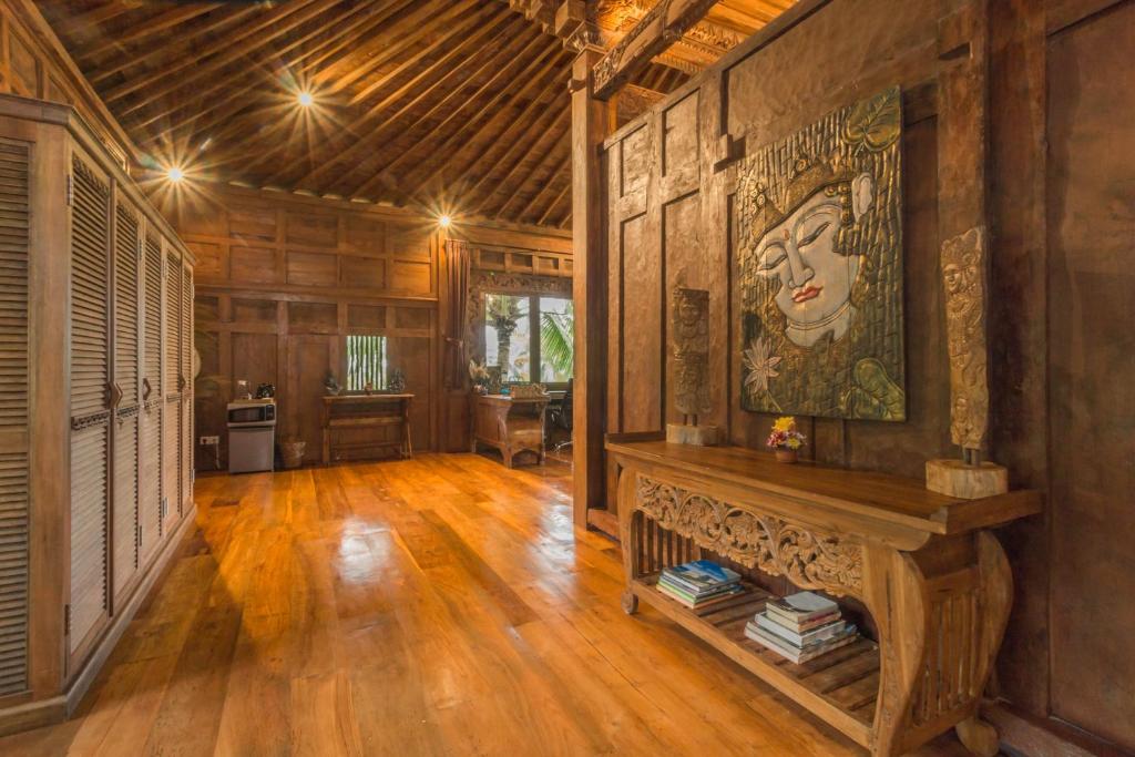 una sala de estar con suelo de madera y una gran pintura en la pared en Masakali Retreat, en Ubud