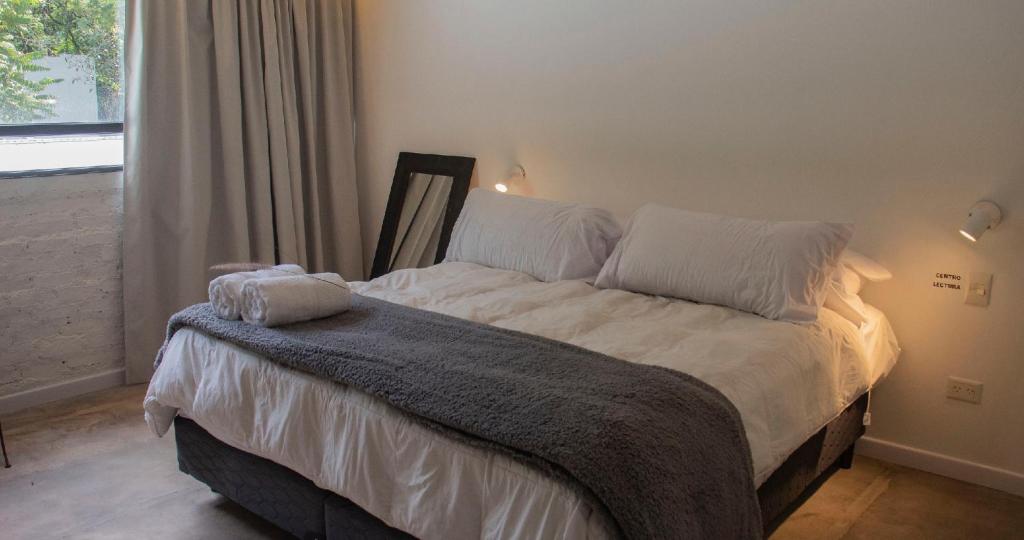 a bedroom with a bed with white sheets and a window at Monte Refugio Urbano in San Salvador de Jujuy