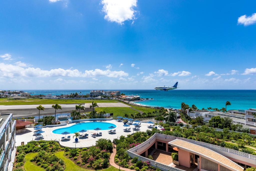 an airplane flying over a resort with a pool and the ocean at Royal Islander Club Resort La Terrasse in Lowlands