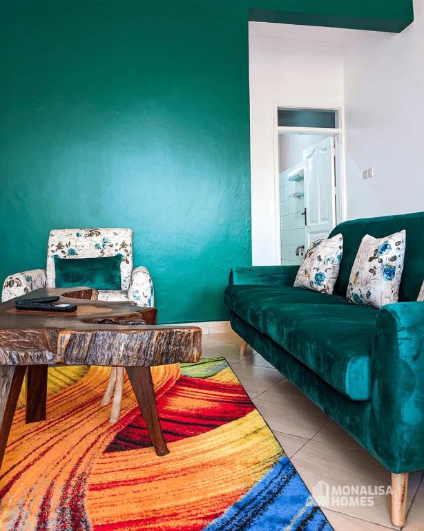 - un salon avec un canapé vert et une table dans l'établissement Green mona unit, à Kampala