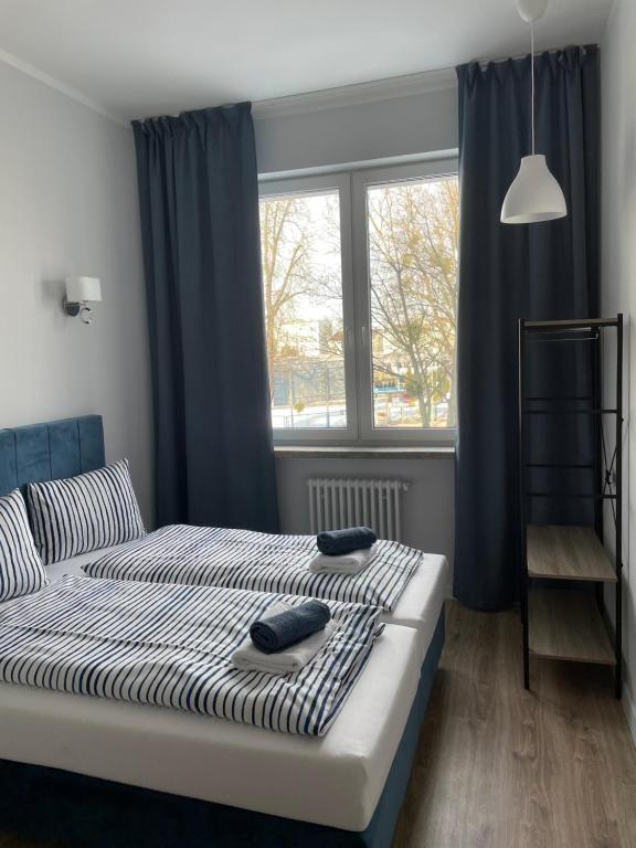 a bedroom with a bed with blue curtains and a window at Aparthotel Dworzec in Elblag