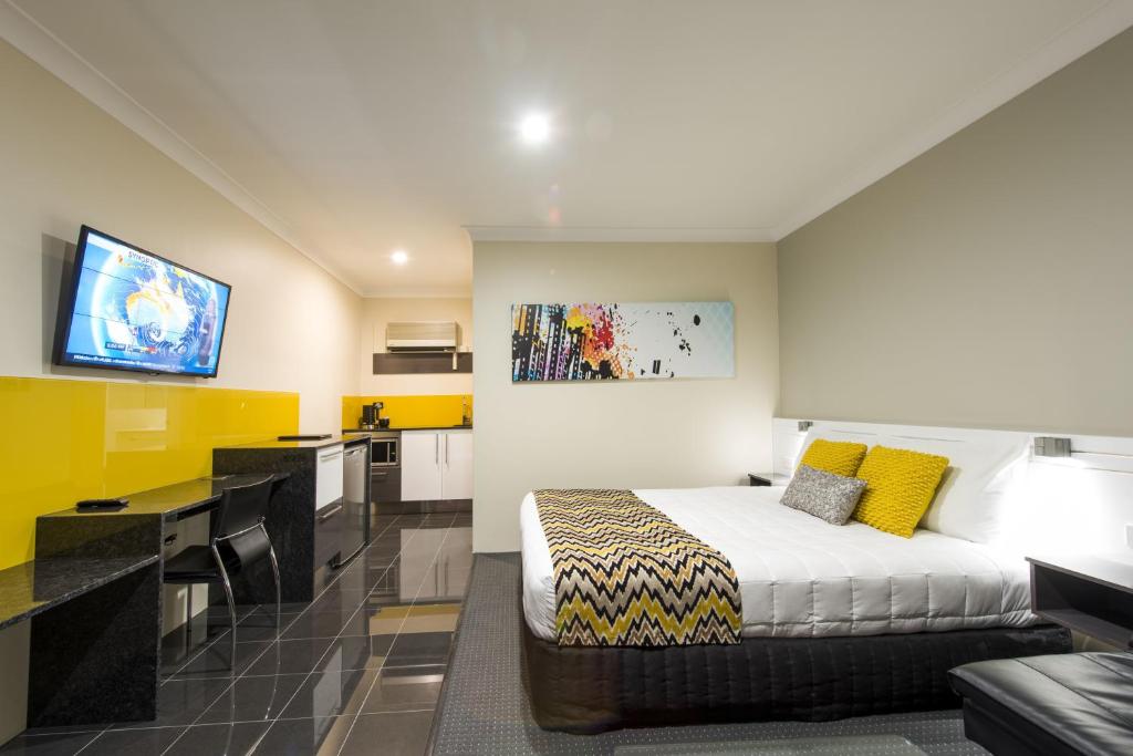 a hotel room with a bed and a kitchen at Abbey Motor Inn in Grafton