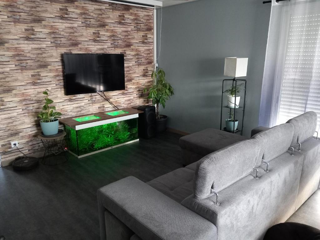 sala de estar con sofá y TV de pantalla plana en Maison au calme, en Belin-Beliet