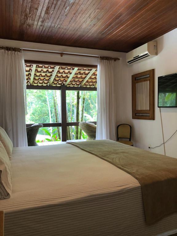 sypialnia z dużym łóżkiem i oknem w obiekcie Sítio Bagatelle com cachoeira e piscina! w mieście Angra dos Reis