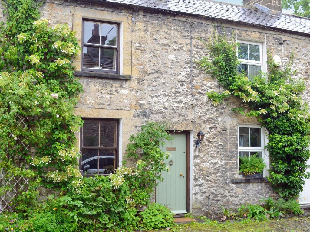 a stone house with a green door and windows at Langcliffe Lock Cottage in Stainforth
