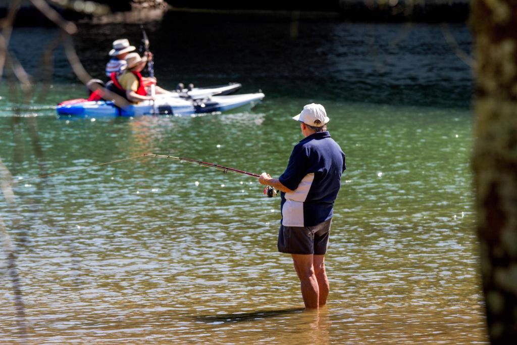 a man standing in the water holding a fishing rod at Reflections Ferry Reserve - Holiday Park in Brunswick Heads