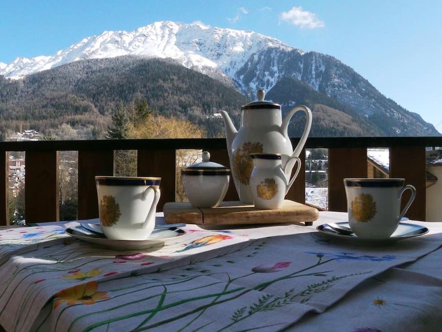 a table with cups and tea pots on a table with a mountain at Appartamento Dolonne Courmayeur in Courmayeur