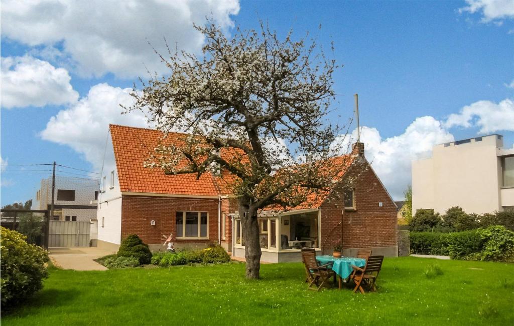 een huis met een tafel en een boom in de tuin bij Cozy Home In Merkem With Wifi in Merkem