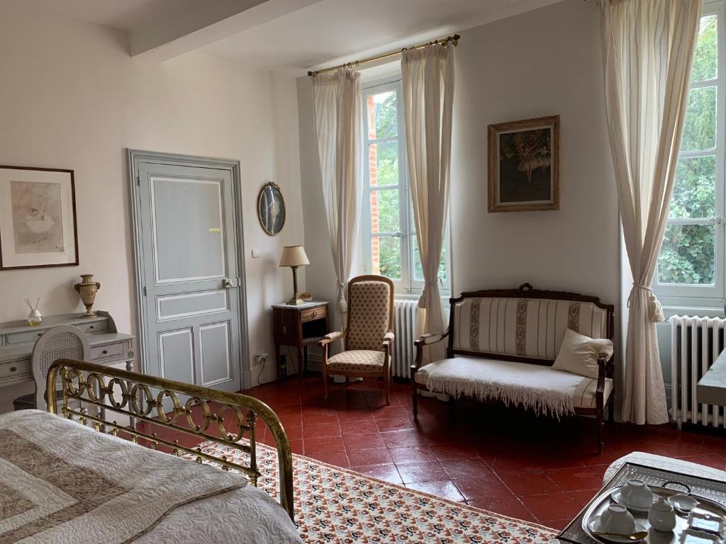 a bedroom with a bed and a chair and window at Le Moulin du Carla in Lavaur