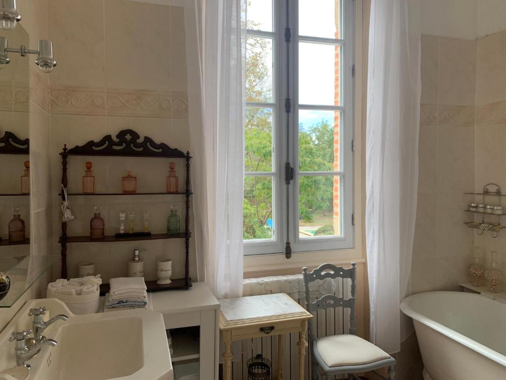 a bathroom with a sink and a tub and a window at Le Moulin du Carla in Lavaur