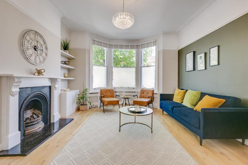 uma sala de estar com um sofá azul e uma lareira em Boutique Victorian 4 Bed House with Garden in Balham em Londres