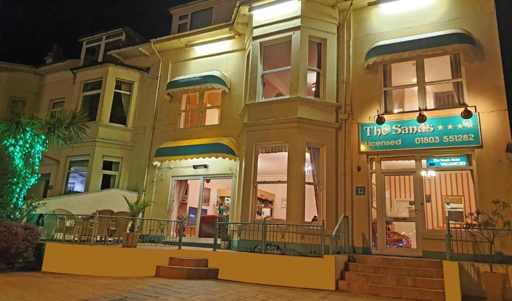 a building with a sign in front of it at night at The Sands Hotel in Paignton
