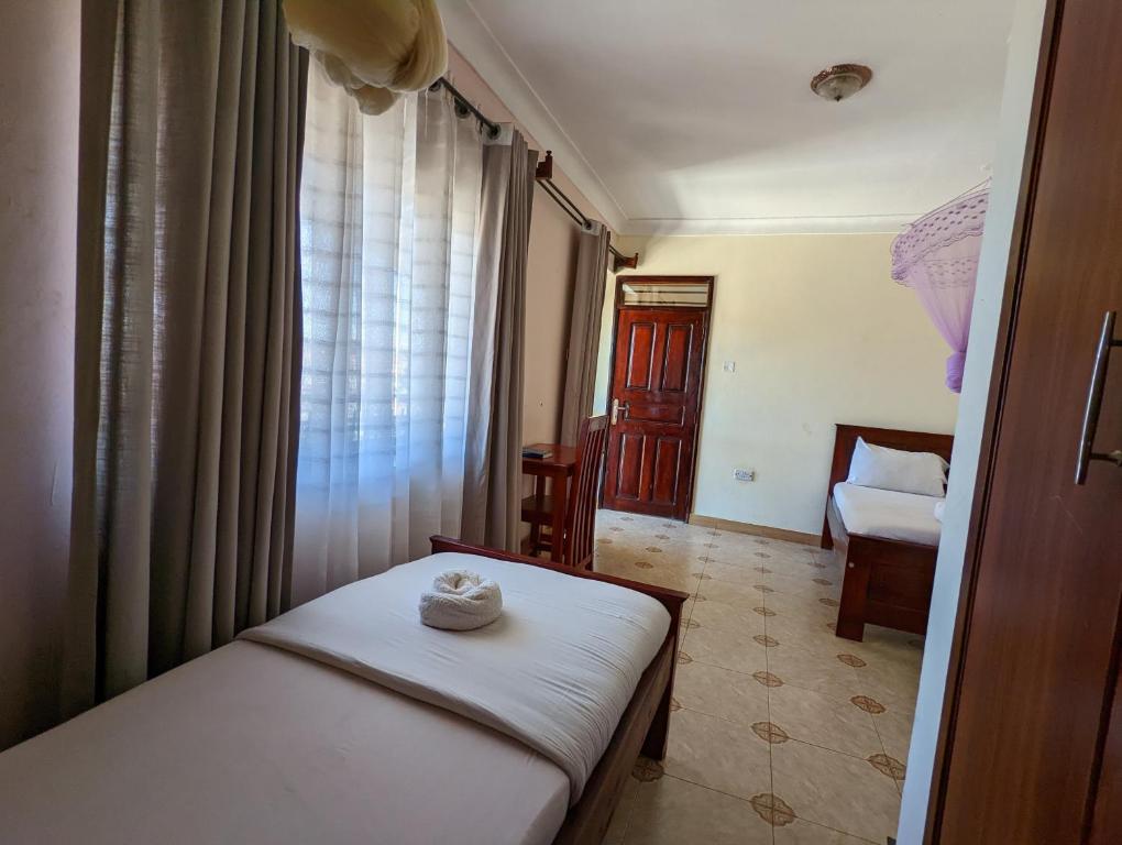 um pequeno quarto com uma cama e uma janela em Kasenene Legacy Hotel em Fort Portal