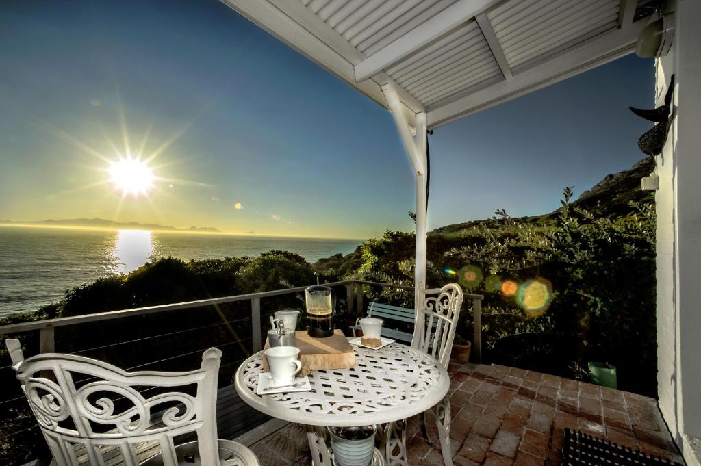 un tavolo e sedie su un balcone con vista sull'oceano di Rocklands Seaside Bed and Breakfast a Simonʼs Town
