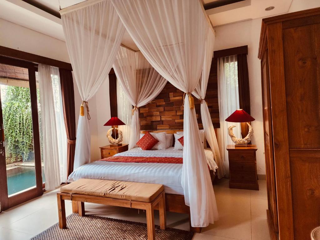1 dormitorio con 1 cama con dosel en Uma Padi Villa, en Ubud