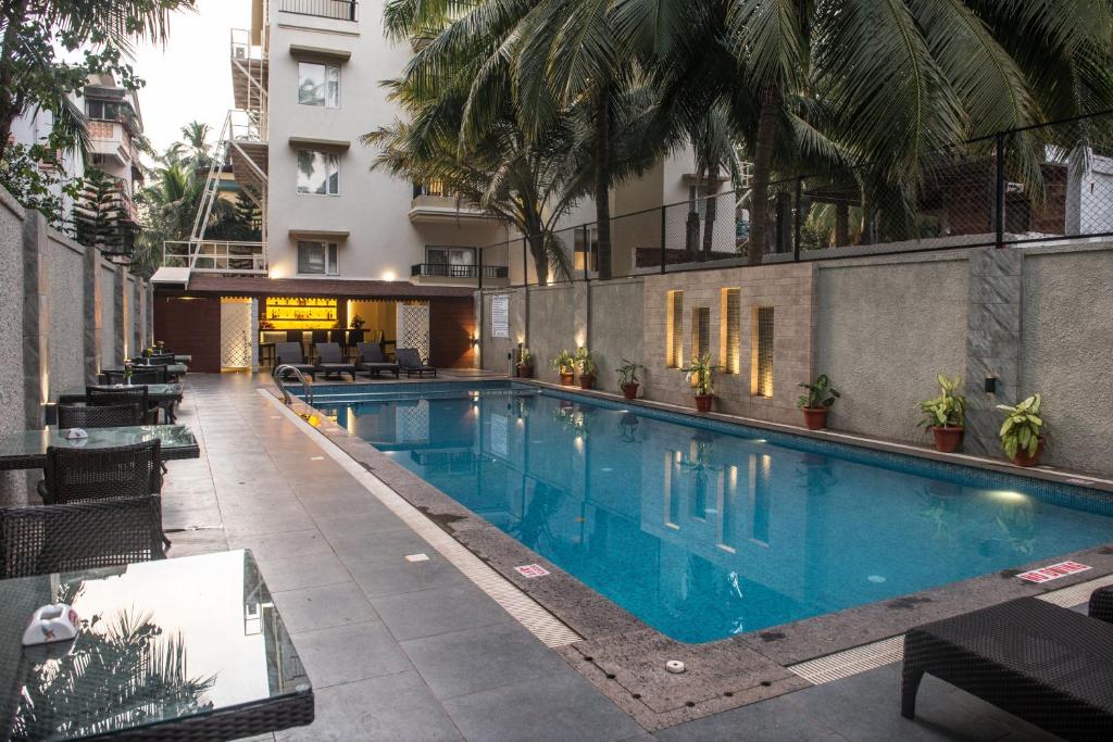a pool at a hotel with tables and chairs at Calangute Towers - AM Hotel Kollection in Calangute