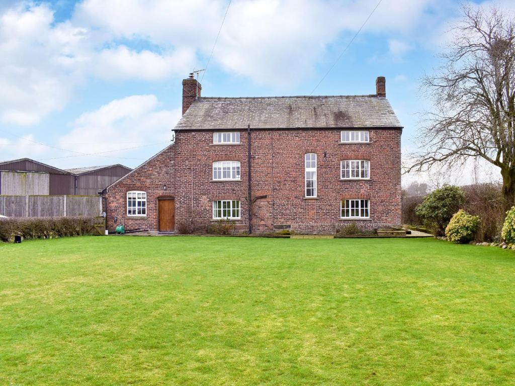 una antigua casa de ladrillo con un gran patio en Brookbank Farm, en Jodrell Bank