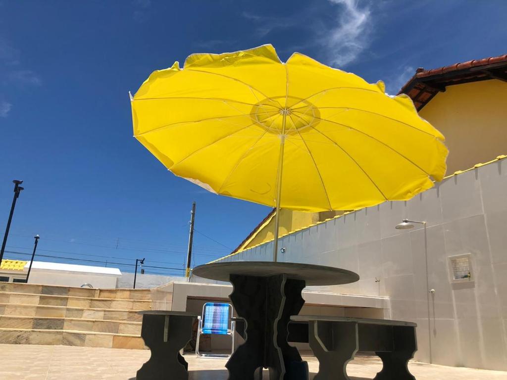 ein gelber Regenschirm auf einem Tisch in der Unterkunft POUSADA COM PISCINA em PERUÍBE SABORES DA VIDA!!! in Peruíbe