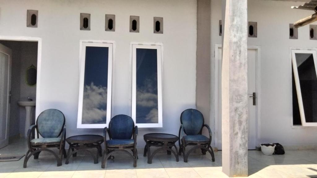 un grupo de sillas en una habitación con ventanas en Marselino Bacpacker's Room en Bajawa
