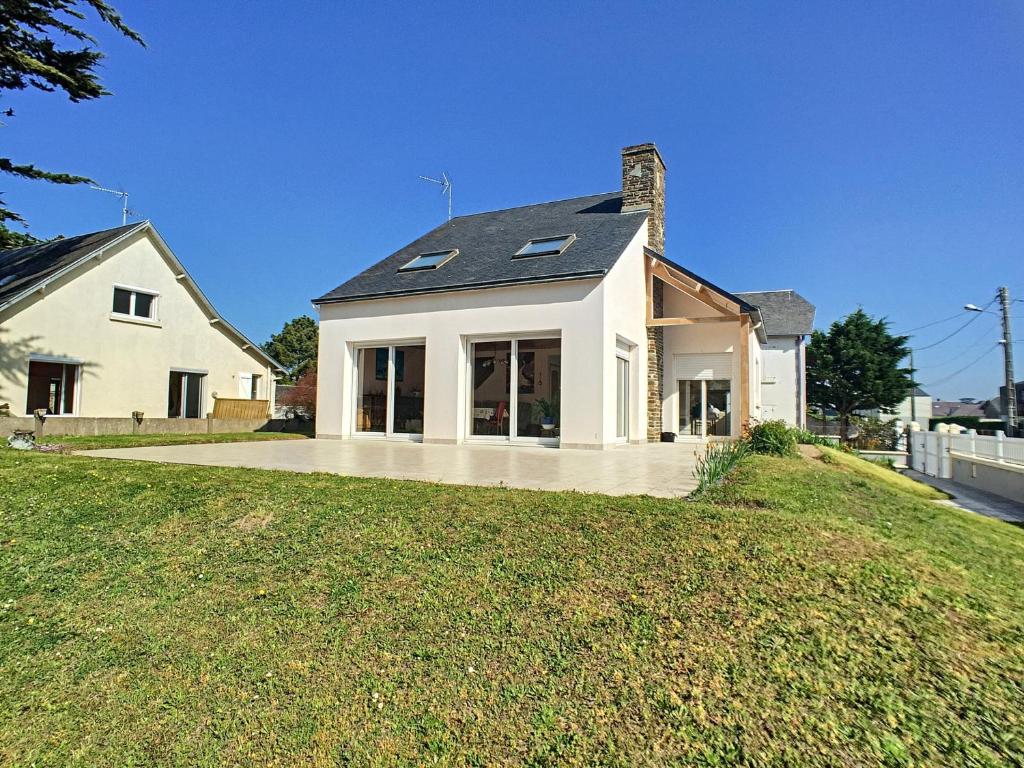 Cette grande maison blanche dispose de fenêtres au-dessus d'une cour. dans l'établissement Villa à 100m de la Plage avec Jardin, Terrasse, et Proche Commerces - FR-1-361-95, à Jullouville