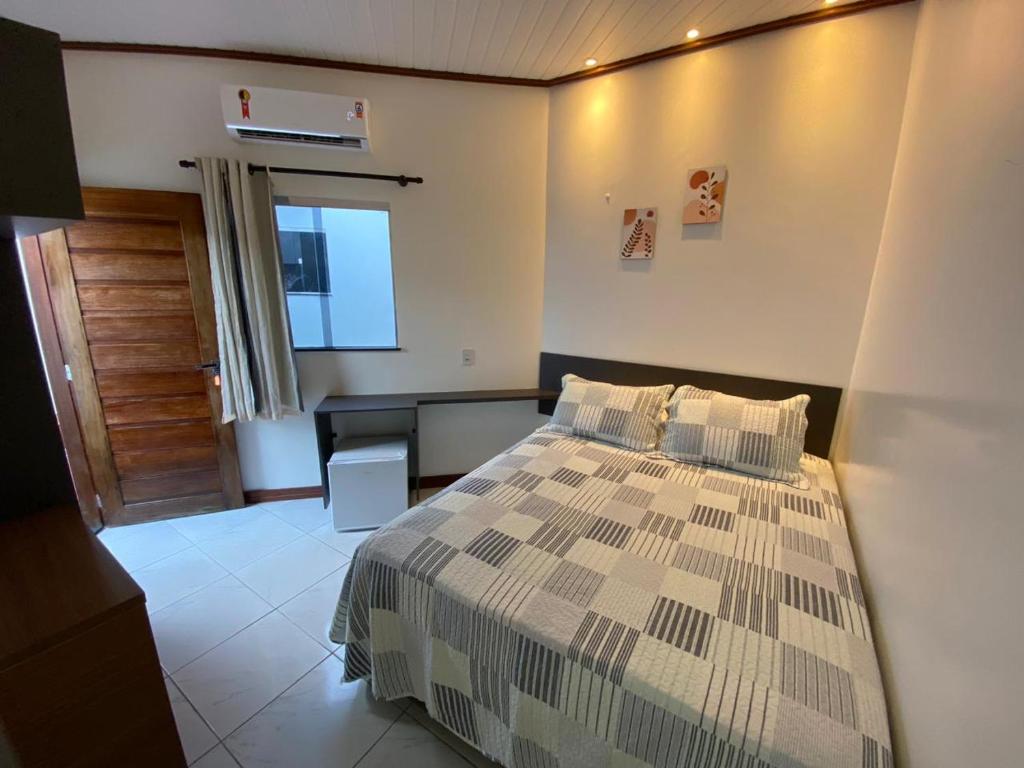 a bedroom with a bed and a desk and a door at Alter Villa Suítes in Alter do Chao