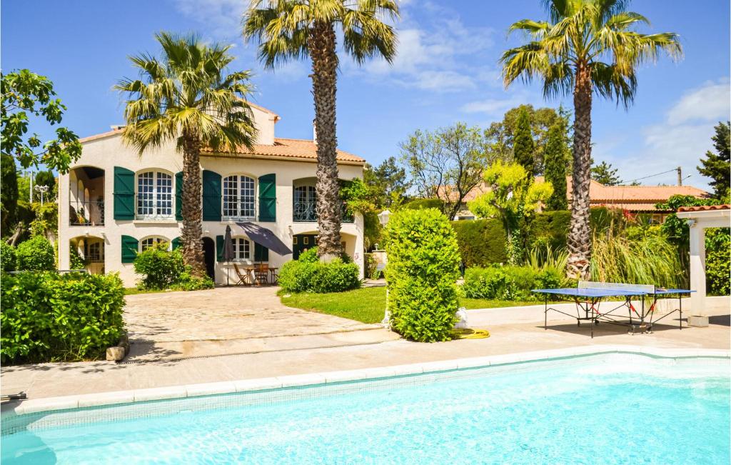 a house with a swimming pool and palm trees at Beautiful Apartment In Pignan With Heated Swimming Pool in Pignan