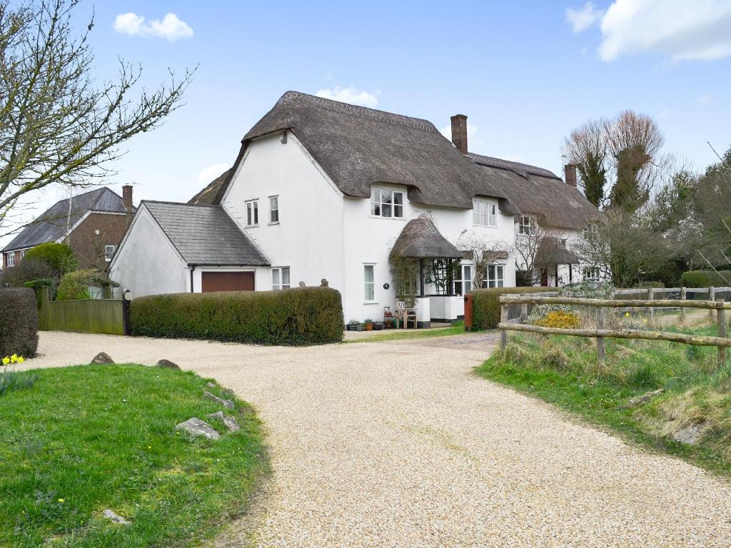 a white house with a fence and a driveway at Peach Cottage in Wool