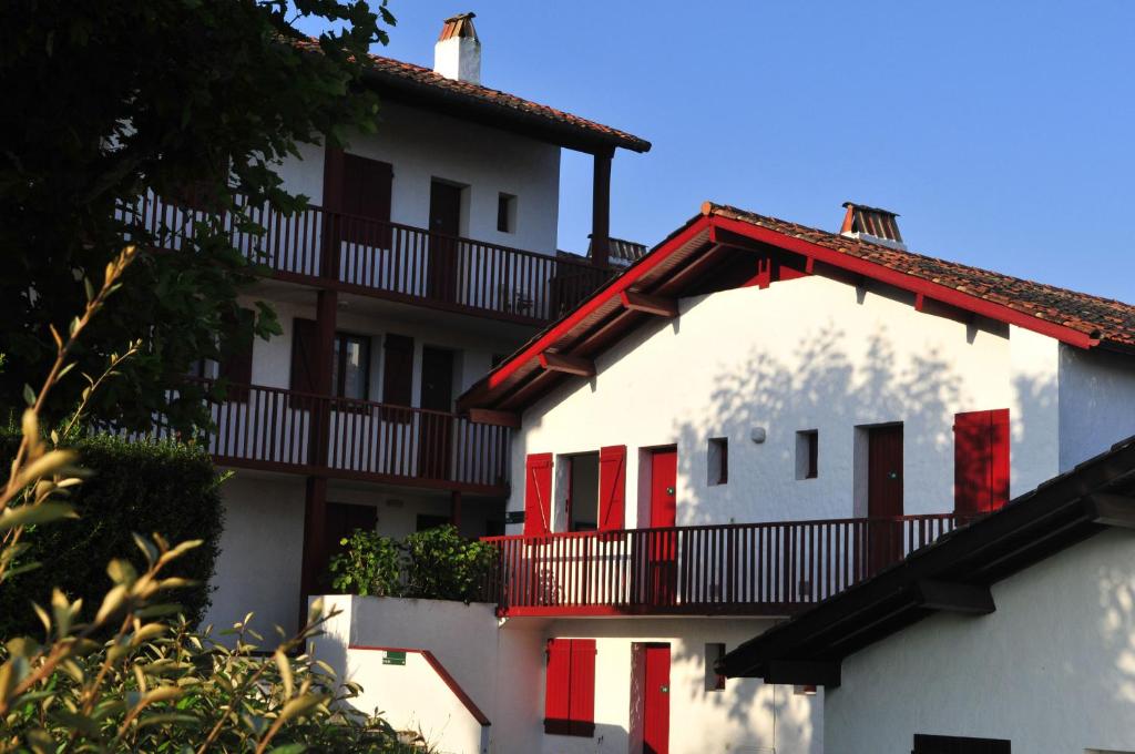 um edifício branco com janelas vermelhas e uma varanda em VVF Pays Basque Sare La Rhune em Sare