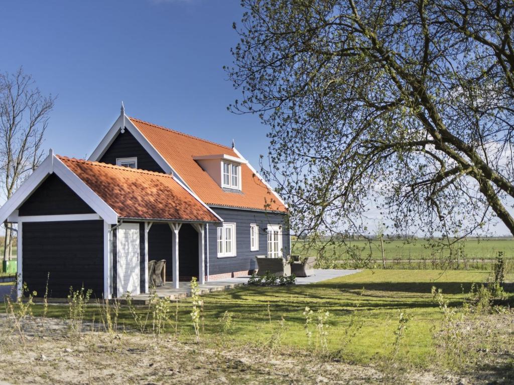 a small black house with an orange roof at Rustic Holiday Home In Wissenkerke With Garden in Wissenkerke