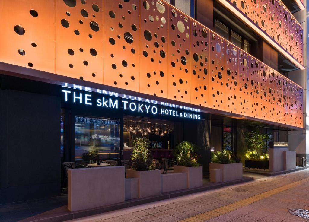 東京的住宿－THE skM TOKYO HOTEL & DINING，一座建筑,上面有读天空的图标