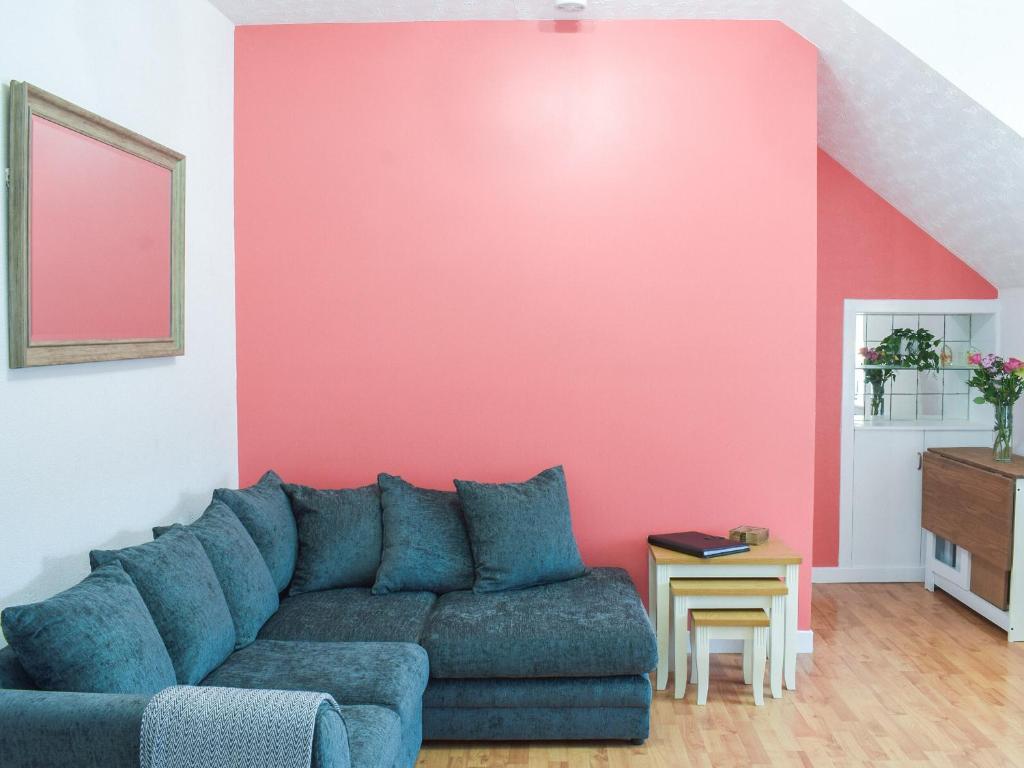 sala de estar con sofá azul y pared rosa en Fiddlers Rest en Ballantrae
