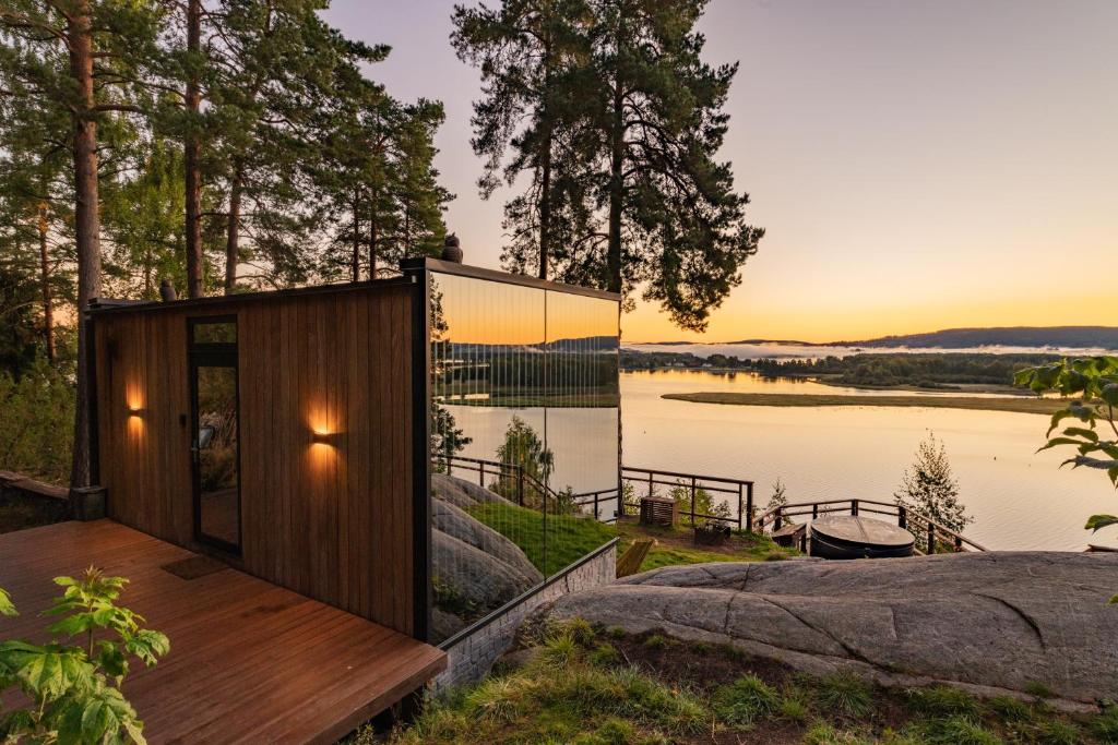 a tiny house with a view of a lake at The WonderInn Mirrored Glass Cabin - Wonderinn Delta in Hektner