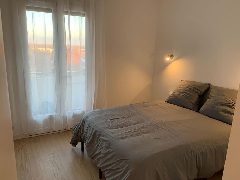 a bedroom with a bed and a large window at Appartement le 48 in Narbonne