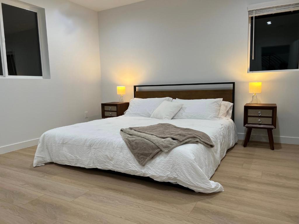 sypialnia z dużym białym łóżkiem z 2 stolikami nocnymi w obiekcie New Luxury Home with DTLA Views - Ideal for Groups w Los Angeles