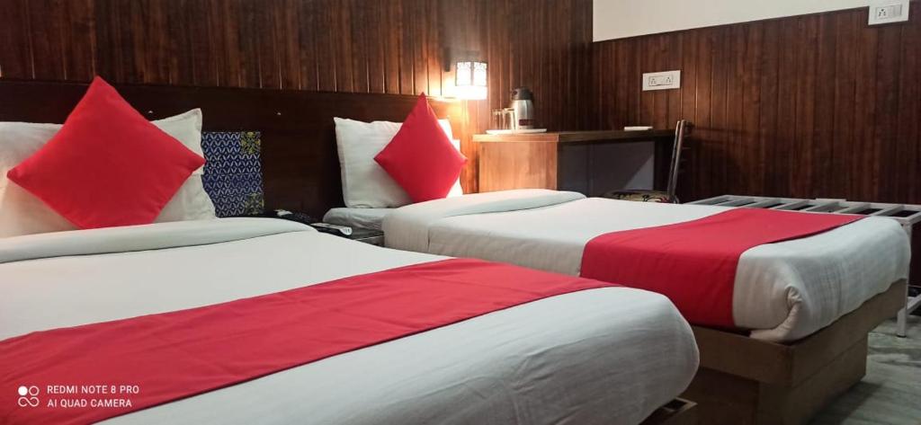 two beds in a hotel room with red pillows at Hotel The Rotisserie By WB Inn in Behror