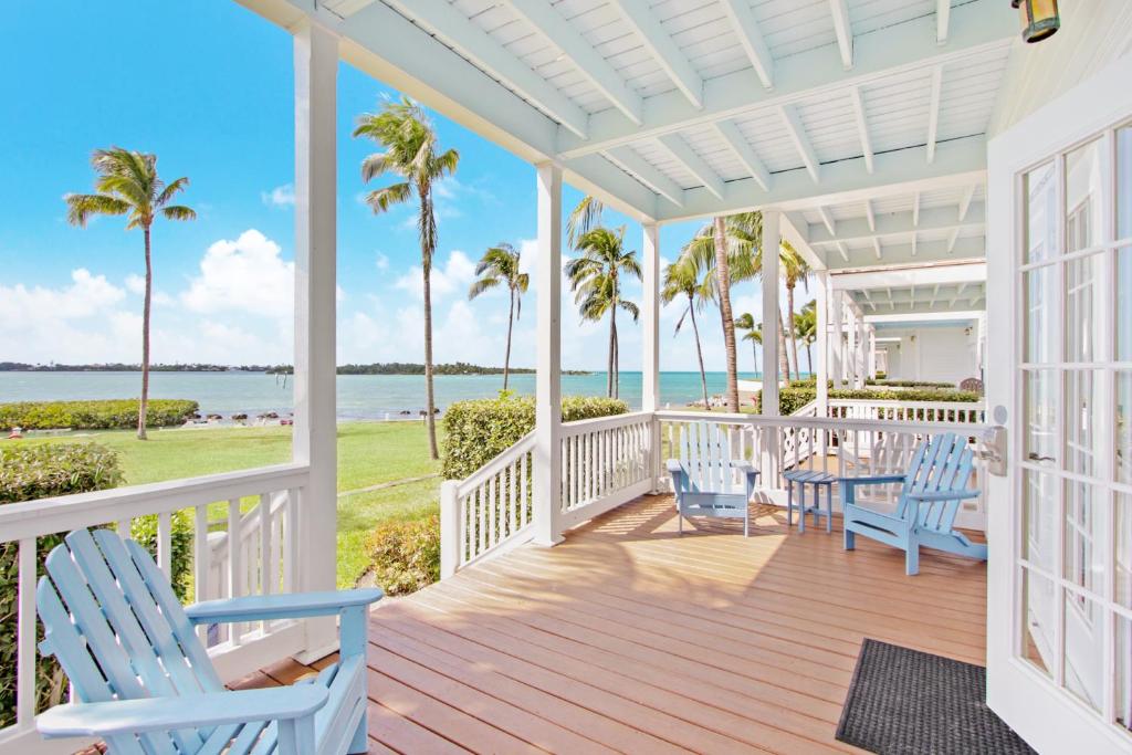 - une terrasse couverte avec des chaises bleues et une vue sur l'océan dans l'établissement Waterfront luxury Villa 54 with sunset views and boat slip townhouse, à Marathon