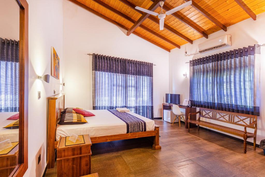 a bedroom with a bed and a desk and windows at Yamu Lanka Inn in Malabe