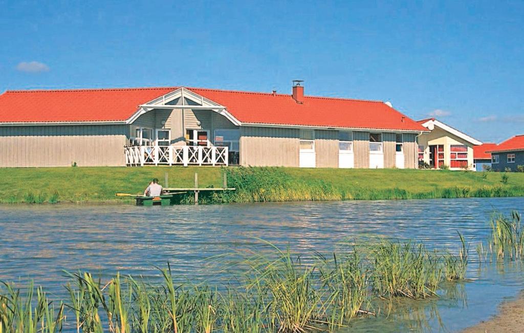 Ein Mann, der auf einem Steg im Wasser vor einem Gebäude sitzt. in der Unterkunft Ferienhaus Nordseebad Otterndorf J in Otterndorf