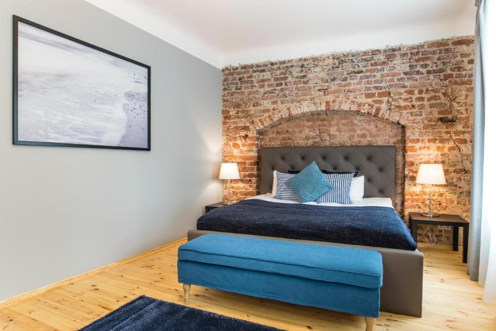 een slaapkamer met een bakstenen muur en een bed bij Colonel Suites & Apartments in Rīga