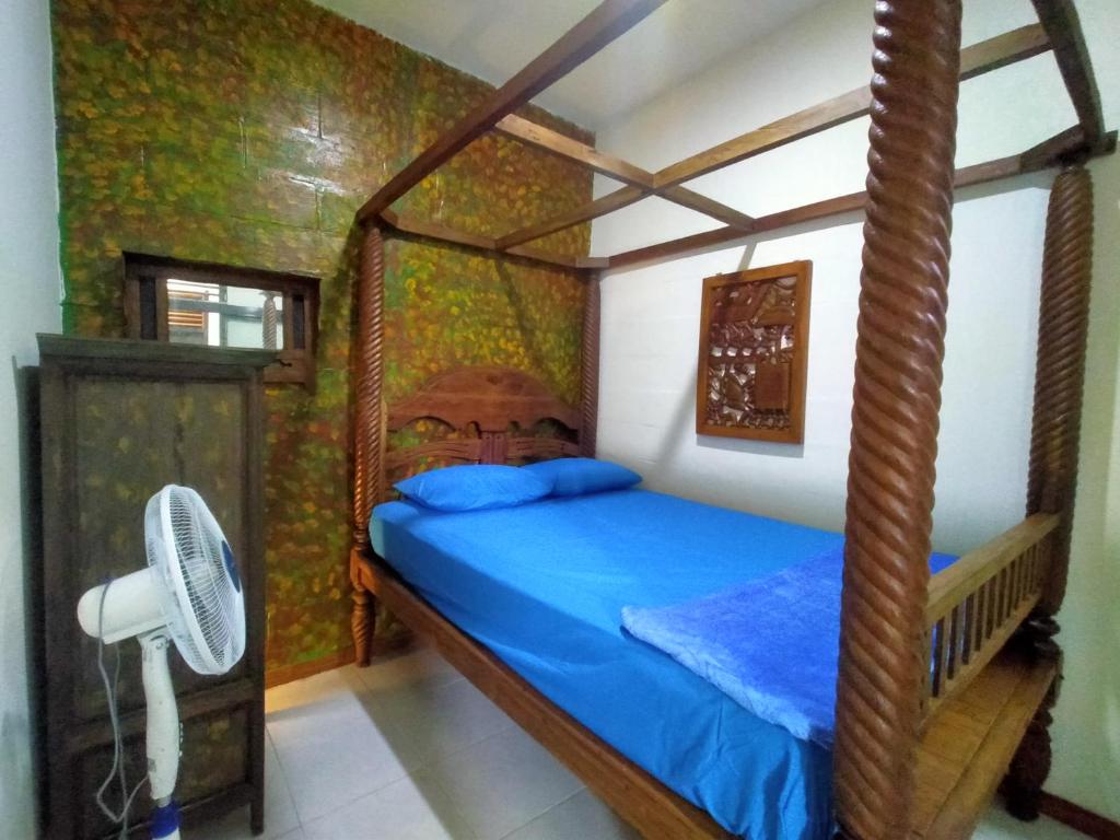 Schlafzimmer mit einem Bett mit blauer Bettwäsche und einem Ventilator in der Unterkunft 8 Up House in Betek
