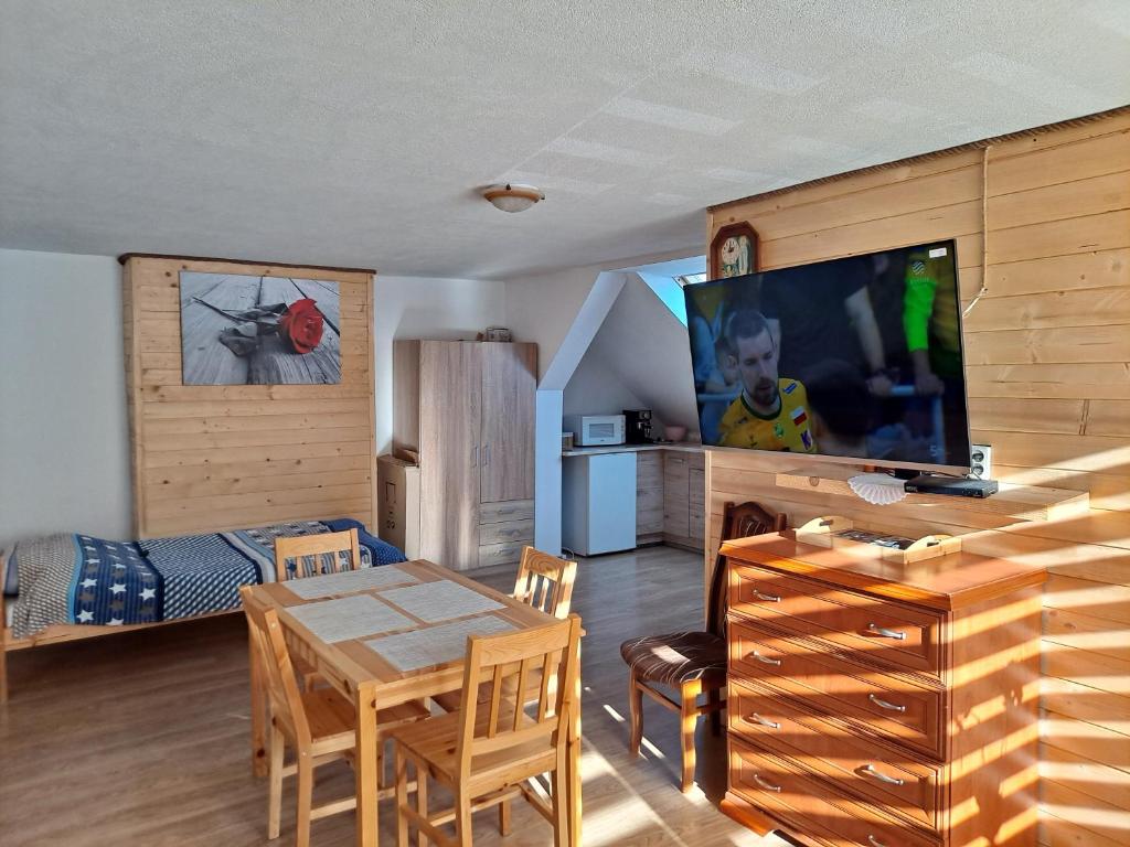 1 dormitorio y sala de estar con mesa y TV. en Agroturystyka pod kasztanem en Lutowiska