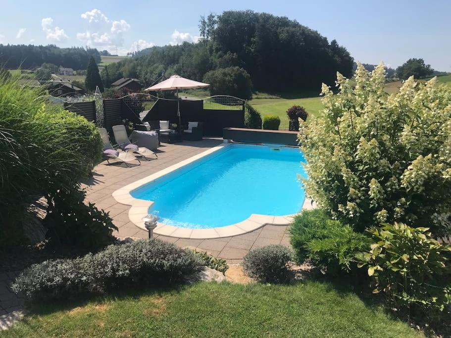 una piscina en un patio con sillas y árboles en Appartement mit Alpensicht, beheiztem Pool, Garten, 