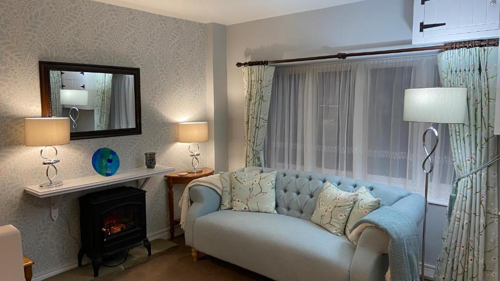 a living room with a blue couch and a fireplace at Apple Blossom Cottage - Spring Cottages, Cheddar in Cheddar