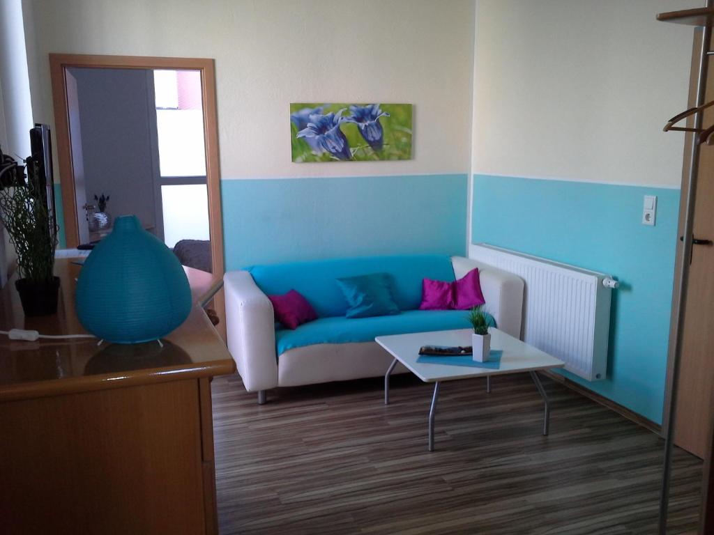 ein Wohnzimmer mit einem blauen Sofa und einem Tisch in der Unterkunft Stadthotel Espelkamp in Espelkamp-Mittwald