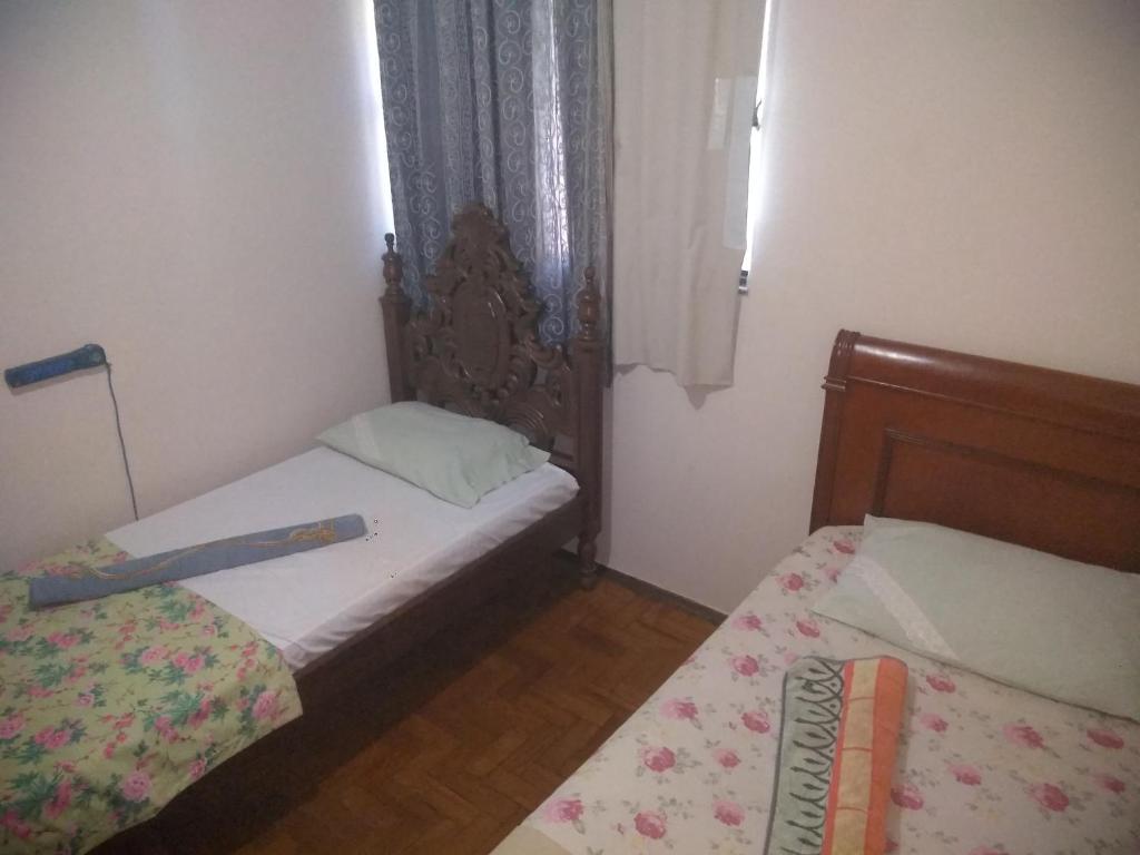 a small bedroom with two beds and a window at HOSTEL ECONÔMICO ELAs in Goiânia