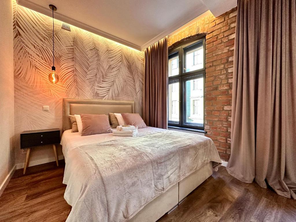 a bedroom with a large bed and a brick wall at PasteLove Okna in Toruń