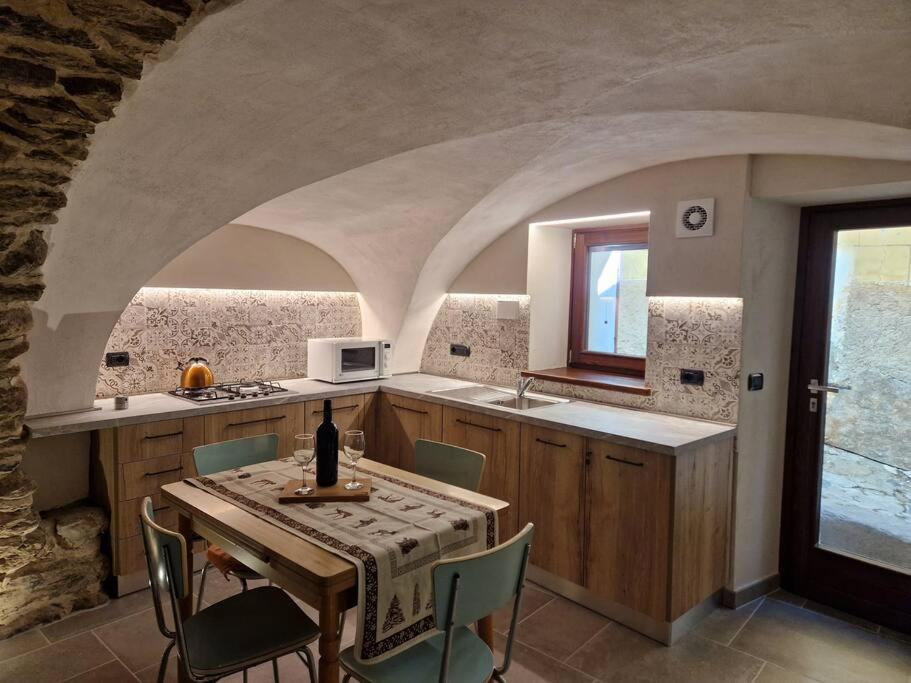 cocina con mesa y sillas y cocina con pared de piedra. en da Annette rifugio montano, en Villaretto